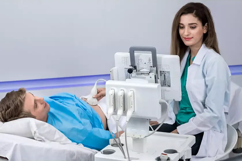 philips innosight врач Врач проводит ультразвуковое исследование брюшной полости мужчине на кушетке с помощью портативной системы Philips InnoSight на мобильной стойке.